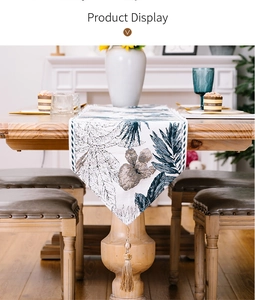 Detail of tropical plant leaf table runner with elegant gold tassel on wooden table