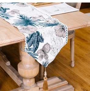 Detail of floral ink wash table runner with tassels on a wooden dining table
