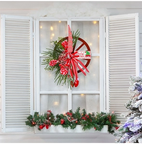 Detail of Christmas wheel wreath with elf hat and Merry Christmas sign on white shutter