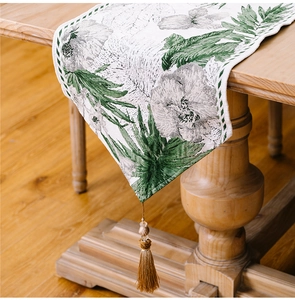 Close-up of ink wash floral table runner with elegant champagne tassel and bead details