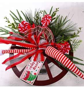 Detail of Christmas wreath with red ribbons and candy decor on a wooden wheel base