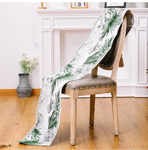 Detail of botanical print table runner with tassels draped over a vintage wooden chair