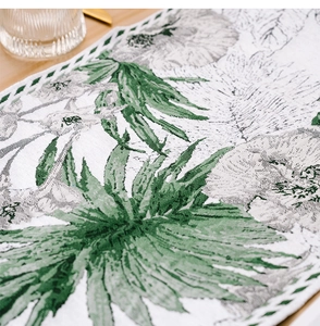 Close-up of jacquard fabric table runner with green ink wash plant pattern and hollow edge