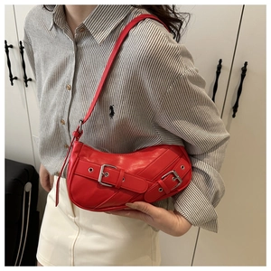 Detail of red leather saddle bag with metallic buckle straps and adjustable shoulder strap