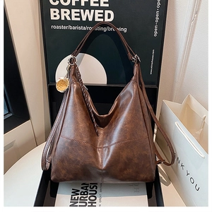 Macro detail of caramel brown leather tote bag with fine stitching and metal charm