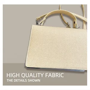 Détail d'un sac à main carré beige avec texture tissée posé sur une veste grise