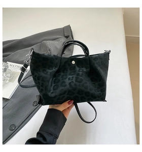 Detailed view of the black leopard print suede handbag with top handles and shoulder strap