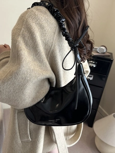 Fashionable black crescent shoulder bag with pleated strap and shiny leather finish