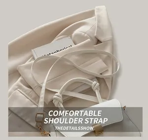 Detail of adjustable shoulder strap and gold metal buckle on white minimalist handbag