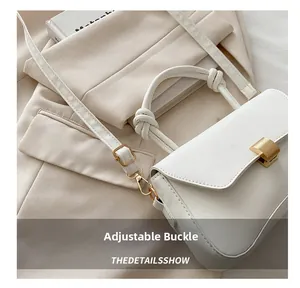Detail of white leather bag with knotted handle and adjustable strap buckle design
