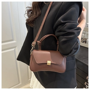 Detail of coffee brown matte leather crossbody bag with elegant gold square twist lock