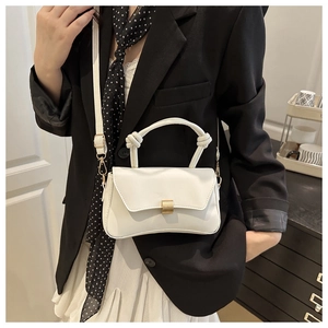 Detail of white crossbody bag with knot handle, gold buckle and adjustable strap