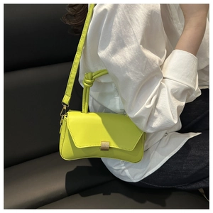 Detail of neon green leather square bag featuring a metal buckle and knotted handle