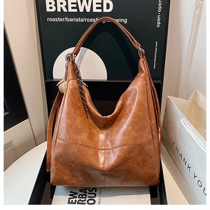 Retro brown leather hobo bag with fringe detail on a premium display shelf