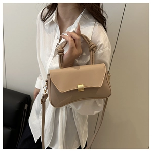 Detail of knot handle and golden metal clasp on beige minimalist crossbody square bag