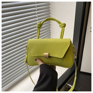 Detail of neon green crossbody bag with knotted handle and golden metal buckle