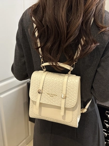 Petit sac à dos beige chic avec texture tressée porté par un mannequin en pull gris clair