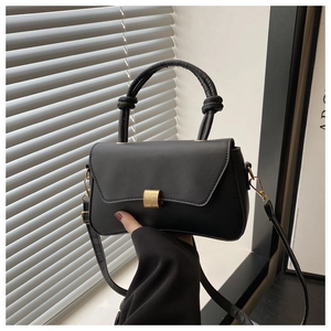 Detail view of black matte leather square bag with gold buckle and knotted top handle