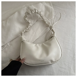 Detail of cream pleated shoulder strap and premium faux leather texture on underarm bag