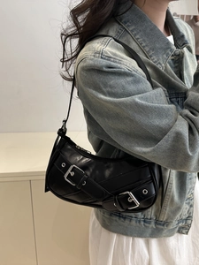 Fashionable black crescent shoulder bag with silver buckles and studs shown on a model