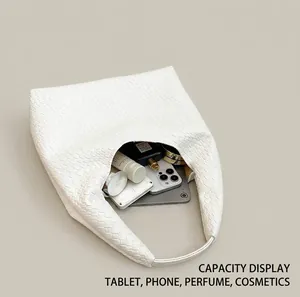Internal view of large white woven leather bag showing storage for tablet and makeup