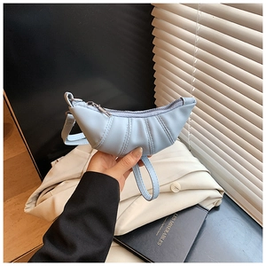 Dettaglio borsa croissant azzurra con design a pieghe e chiusura a zip