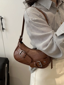 Brown vintage semi-circular underarm bag with decorative metal buckle straps and silver eyelets