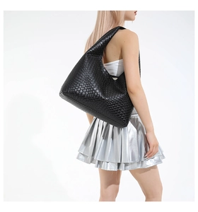 Detail view of a black woven leather tote bag featuring a moon-shaped handle and intrecciato style