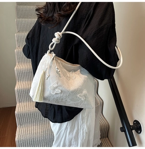 Detail of white butterfly tote bag with delicate 3D embroidery and side fringe tassel