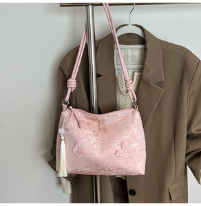 Detail of pink lace shoulder bag featuring 3D butterfly appliqués and tassel pearl pendant