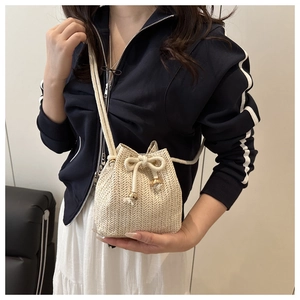 Macro view of cream woven bucket bag featuring herringbone texture and gold beads