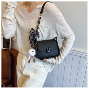 Detail of black leather square bag with silk scarf chain strap and plush monster charm