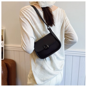 Model wearing a black minimalist saddle shoulder bag with matte leather finish