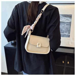 Detail of beige crossbody bag featuring a silk scarf bow and square decorative buckle