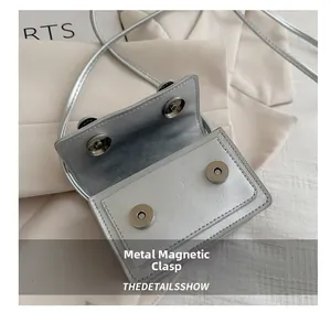 Detail view of silver mini crossbody bag showing dual magnetic snap closures and texture