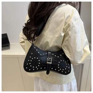 Détail du sac bandoulière noir texture crocodile avec rivets dorés et boucle de fermeture