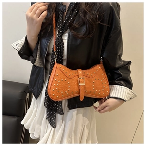 Vue détaillée du sac orange motif crocodile à clous dorés porté par un mannequin