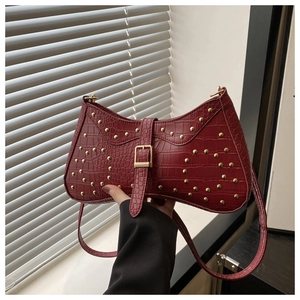 Détail macro du sac sous le bras en cuir crocodile rouge foncé avec rivets dorés