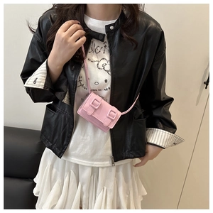 Close-up of pink mini crossbody bag with double buckle straps worn on shoulder