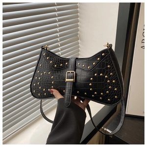 Détail du sac en cuir texture crocodile noir avec rivets dorés et boucle chic