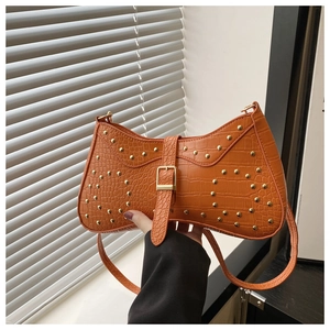 Détail du sac selle orange motif crocodile avec rivets dorés et boucle en métal