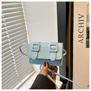 Detail of light blue mini crossbody bag featuring fine cross grain texture and buckle straps