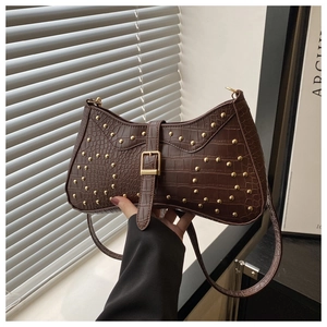 Détail du sac texture crocodile marron foncé avec clous dorés et design rétro incurvé