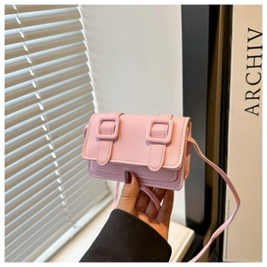 Detail view of mini pink square crossbody bag with decorative buckles and slim shoulder strap