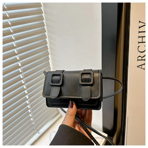 Detail of a black leather square crossbody bag featuring classic decorative belt buckles