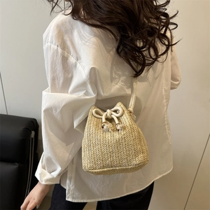 Stylish woven straw bucket bag with white drawstring and V-shaped texture for beach travel