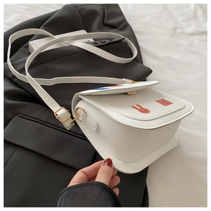 Detail of white PU leather crossbody bag with rabbit graphic print and gold metal buckle