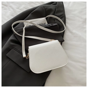 Detail of the white PU leather handbag featuring a gold hardware buckle on a suit jacket