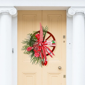 Christmas wreath with wooden wheel, evergreen branches, and Merry Christmas sign on a door