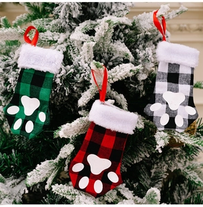 Trois chaussettes de Noël à carreaux avec empreintes de pattes sur branches enneigées